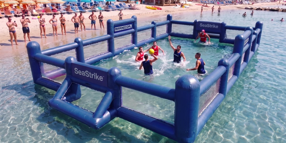L'arena in acqua bassa davanti a uno stabilimento, con una partita 3 contro 3 in corso e alcune persone che guardano dalla battigia